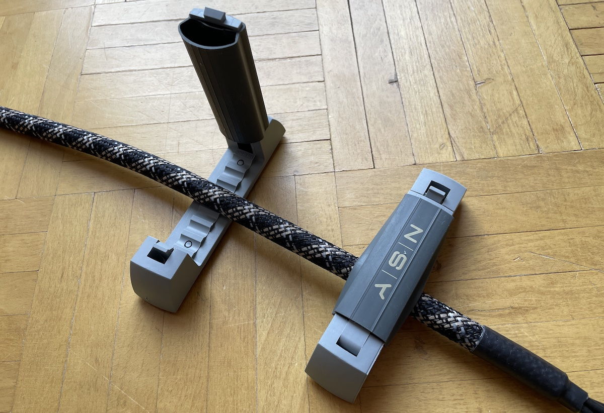 Zwei aufnahmefähige Kabel-Klemmen mit selbstklebender Rückseite gehören zum Lieferumfang.